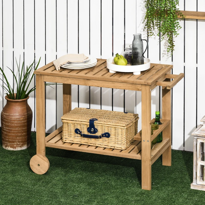 Wooden outdoor serving cart with plates, fruits, and wicker basket on artificial grass setup.