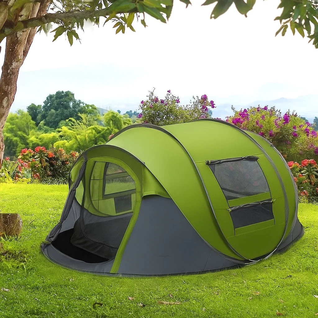 Green and gray pop-up family tent set up on grass, surrounded by flowers, trees, and distant mountains.