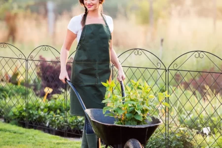women working near metal fence panel with plants and greenery around.