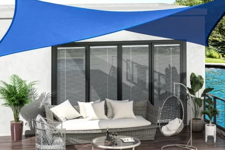 Tan shade sail providing backyard sun protection over grass and outdoor seating.