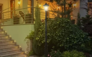 Residential lamp post illuminating a cozy porch with elegant landscaping at night.