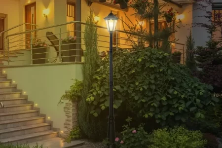 Residential lamp post illuminating a cozy porch with elegant landscaping at night.