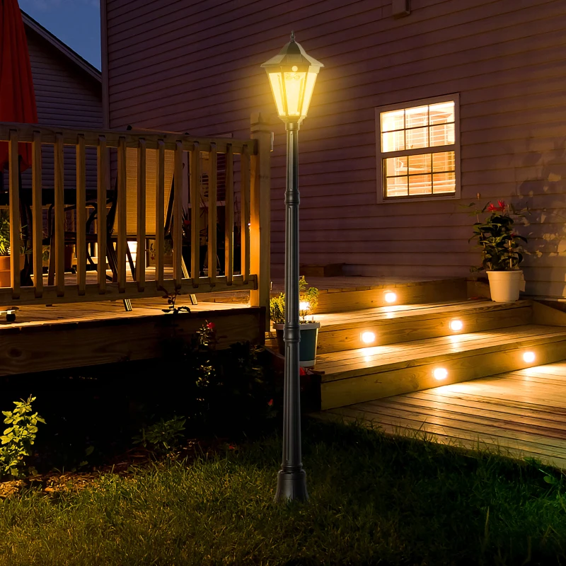 Illuminated outdoor lamp post beside wooden deck at night with glowing stair lights