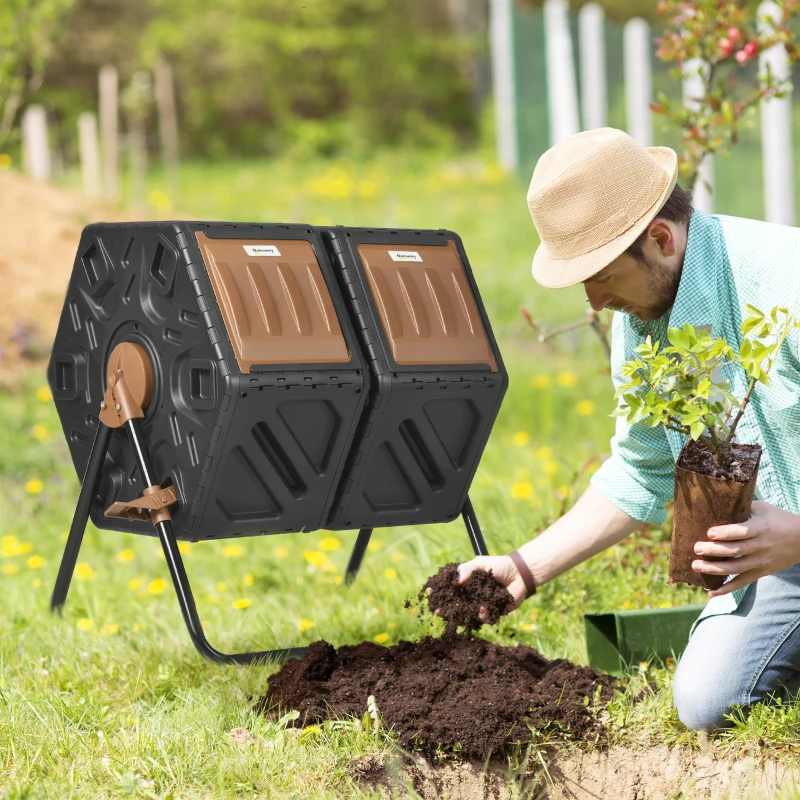 Man using compost from dual-chamber tumbling composter for planting in backyard garden.