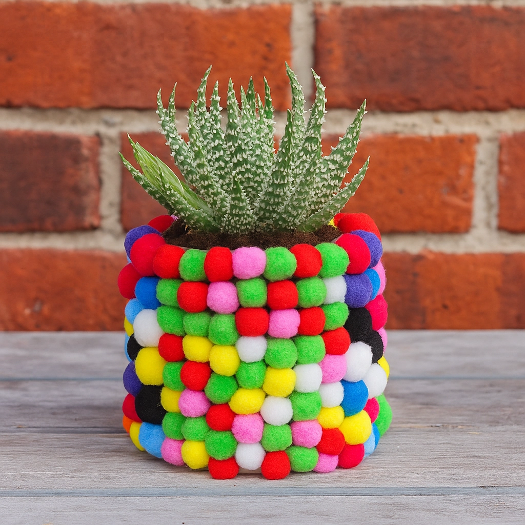 Colorful pom-pom decorated flower pot with succulent plant for playful, creative home decor.