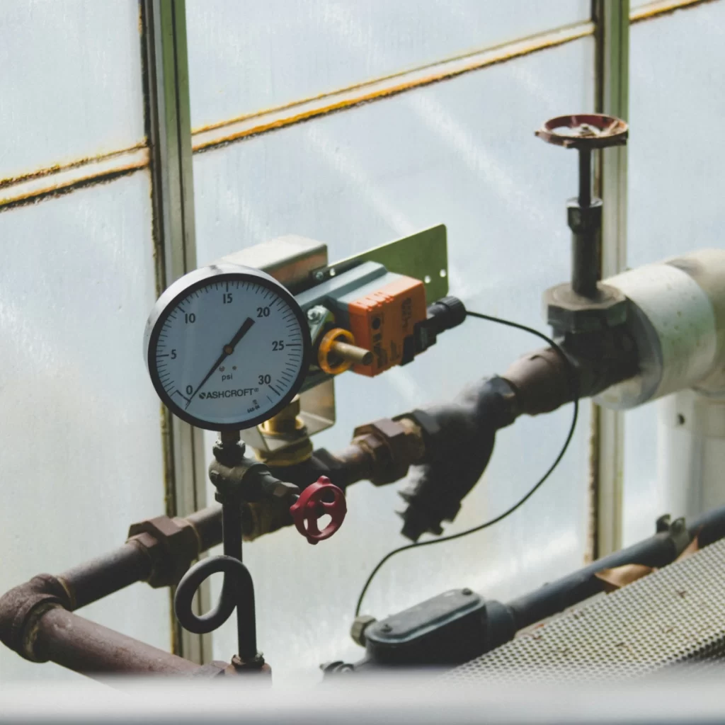 A pressure gauge controlling the climate in a greenhouse for optimal plant health.