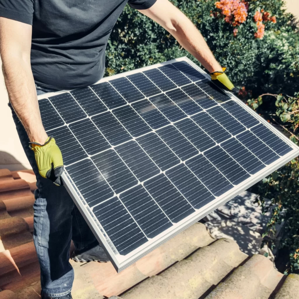 A person installing solar panels to create eco-friendly heating for a greenhouse.