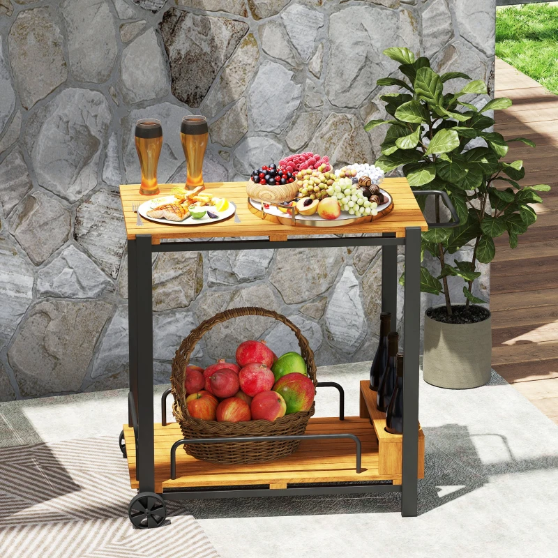 Outdoor bar cart with wooden top, full of fruits, snacks, and drinks on patio beside plants.