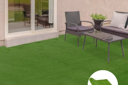 Clean artificial turf patio with glass table, black chairs, and plant pot near sliding door.