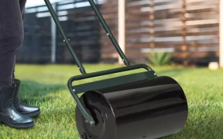 Person using DIY lawn roller on grass to level and compact soil in backyard.