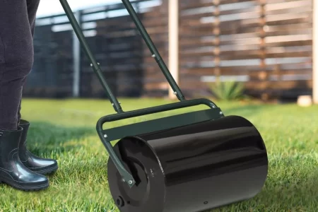 Person using DIY lawn roller on grass to level and compact soil in backyard.