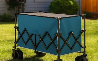 Compact folding wagon loaded with outdoor gear, parked on grass with trees in background.