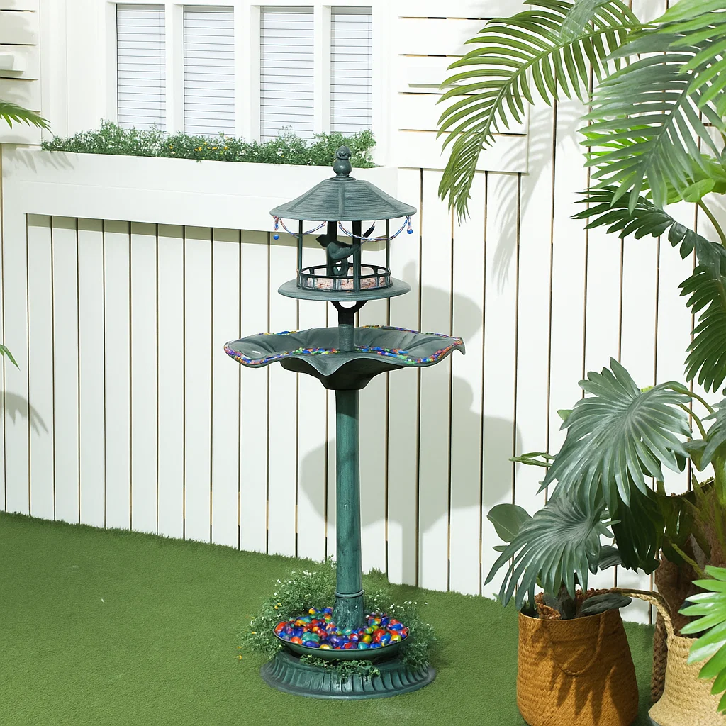 Decorative bird bath filled with colorful marbles and vibrant flowers.