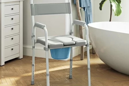 Portable commode chair in modern bathroom with bathtub and wooden flooring