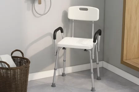 White shower chair with black armrests placed in a corner of a tiled bathroom