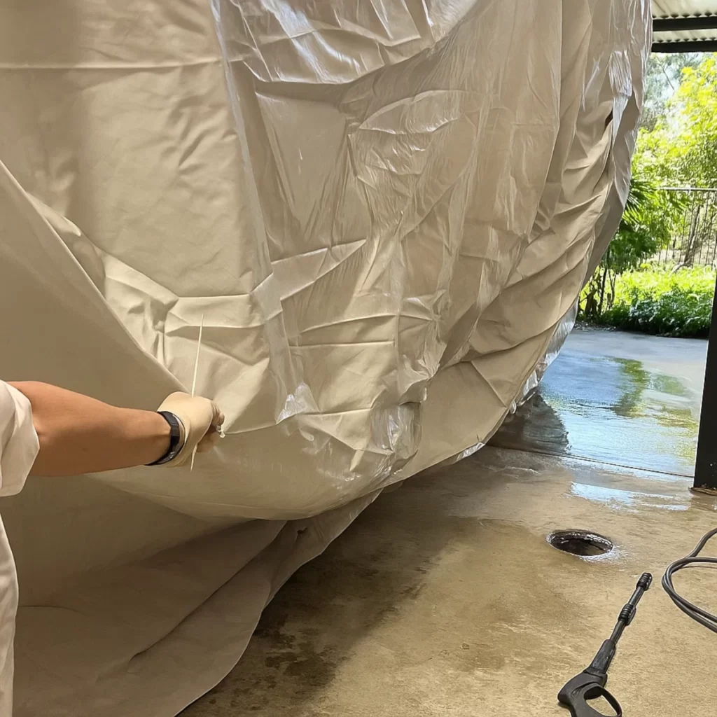Person lifting wet tent fabric to air dry it after outdoor use and cleaning.