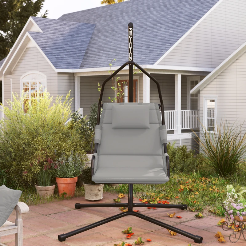 hammock chair with cushions hanging from a metal stand in a backyard.
