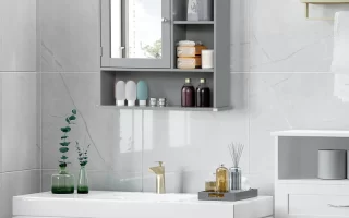 Gray wall-mounted bathroom cabinet with mirror, open shelves, and toiletries above modern sink.