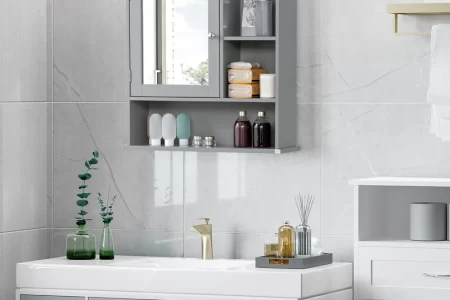 Gray wall-mounted bathroom cabinet with mirror, open shelves, and toiletries above modern sink.