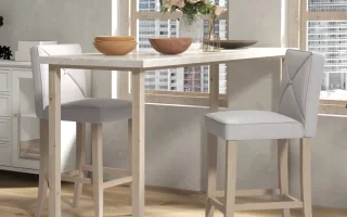 White bar table with two wooden bar stools in a modern, sunlit dining area.