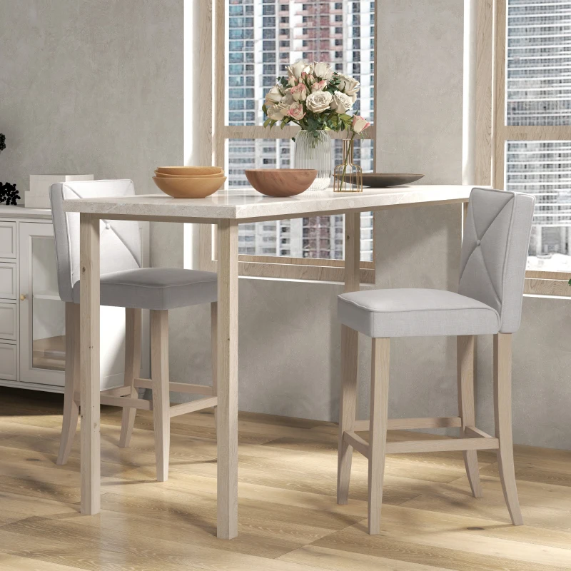 White bar table with two wooden bar stools in a modern, sunlit dining area.