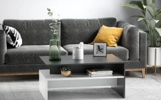 Modern living room with a two-tone coffee table, grey couch, framed art, and indoor plants.