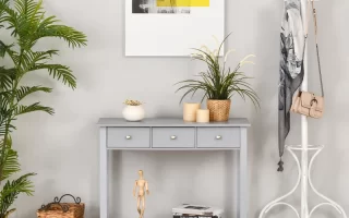 Light grey console table with drawers in entryway, styled with plants, books, candles, and wall art.