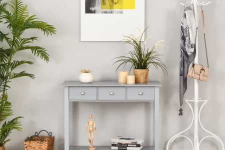 Light grey console table with drawers in entryway, styled with plants, books, candles, and wall art.