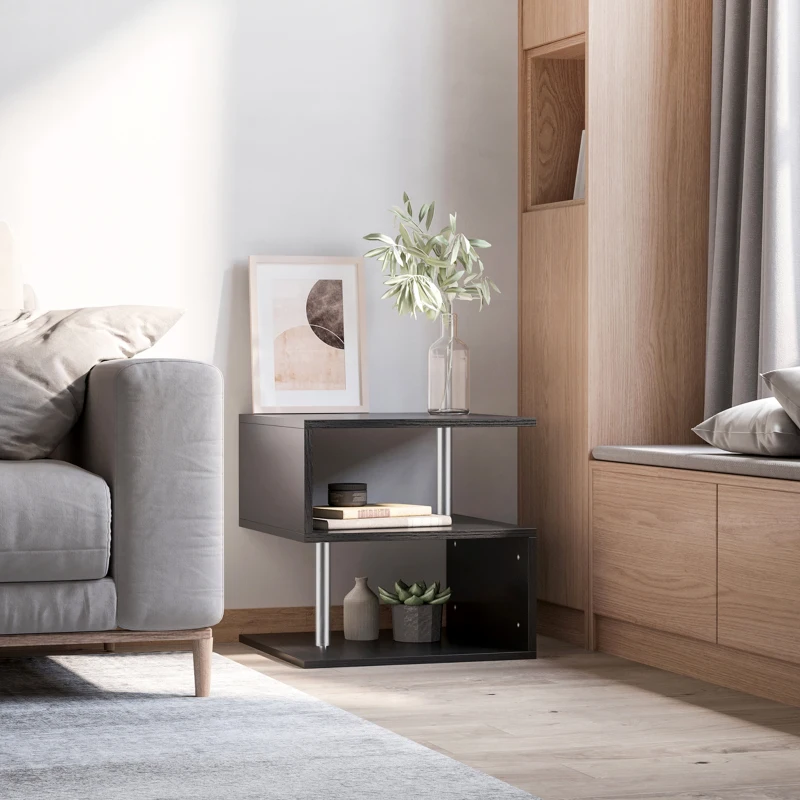 Modern black end table styled with books, a vase, and artwork beside a grey sofa.