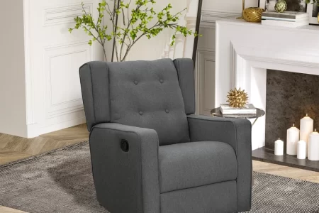Grey tufted recliner placed in a bright room with a fireplace and indoor plant decor.