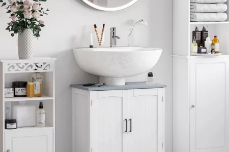 Modern bathroom with round mirror, white vanity, floral decor, and organized open shelves.