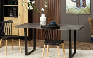 Modern dining table with black chairs, minimalist dishes, and floral centerpiece in white vase.