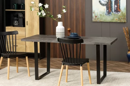 Modern dining table with black chairs, minimalist dishes, and floral centerpiece in white vase.