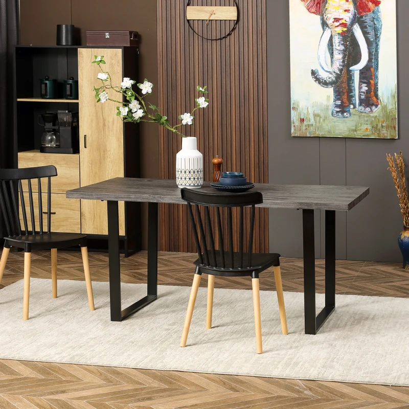 Modern dining table with black chairs, minimalist dishes, and floral centerpiece in white vase.