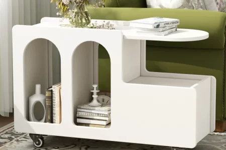 Modern white end table on wheels styled with books, flowers, and curved cutouts for storage