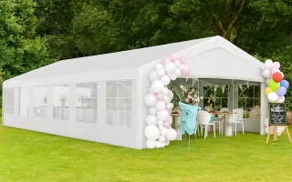 White outdoor canopy tent with balloon decor set up for a party in a grassy area.