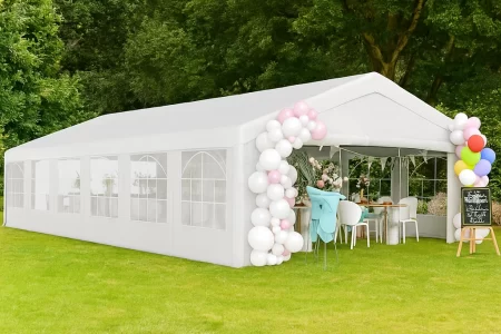 White outdoor canopy tent with balloon decor set up for a party in a grassy area.