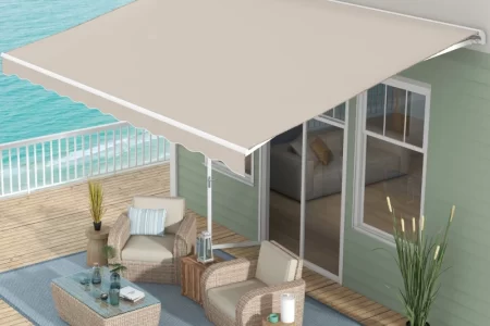 Beige retractable awning installed over coastal deck with wicker patio furniture and ocean view.