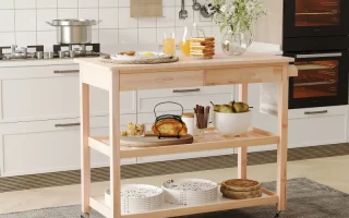 Light wood kitchen island cart with drawers and shelves styled for breakfast in a modern white kitchen.