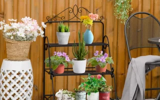 Black metal plant stand before painting, placed outdoors on cardboard for a DIY makeover.