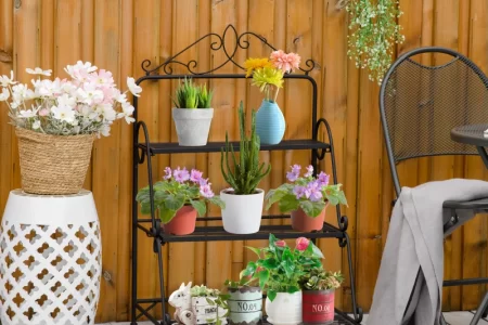 Black metal plant stand before painting, placed outdoors on cardboard for a DIY makeover.