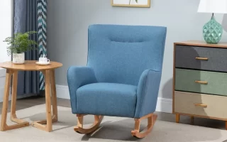 Finished blue fabric rocking chair placed on a rug beside a table and dresser