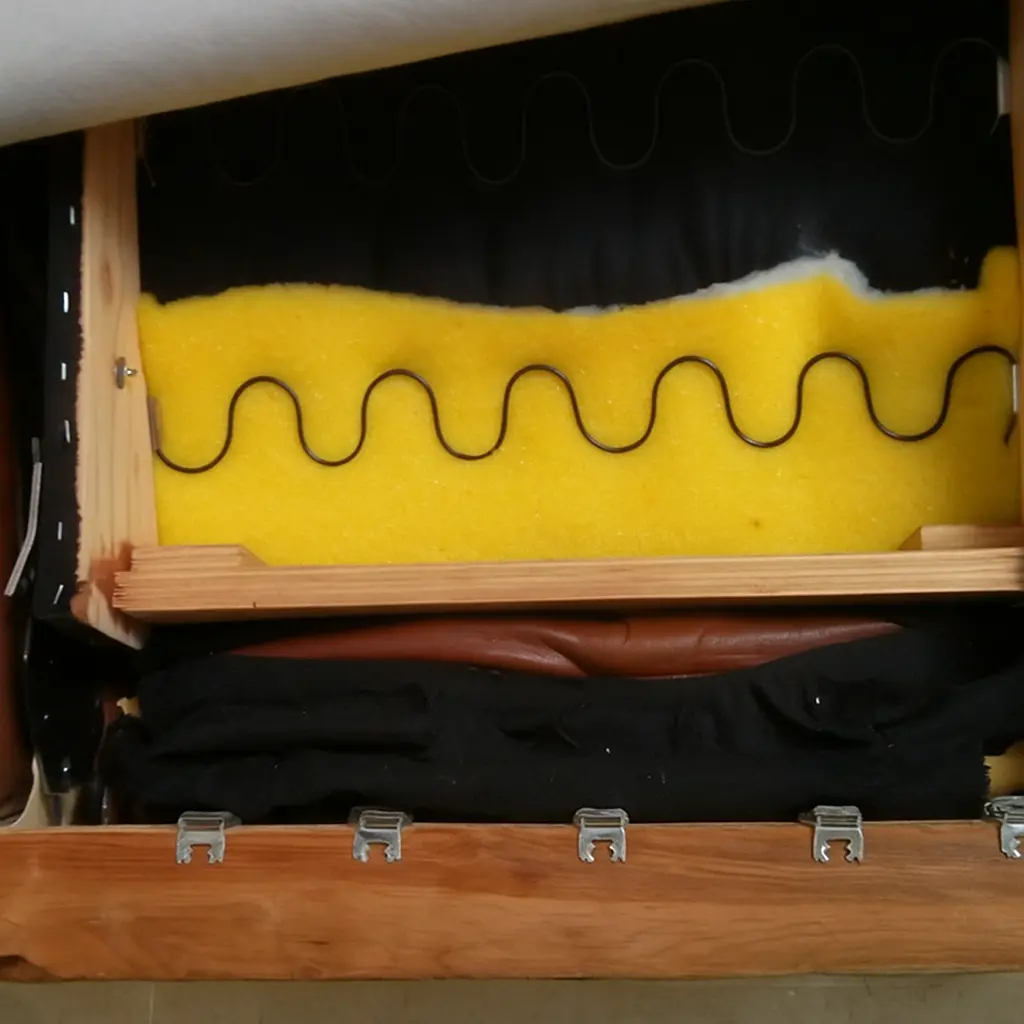 Close-up of recliner seat interior showing foam padding, zigzag springs, and wooden frame.