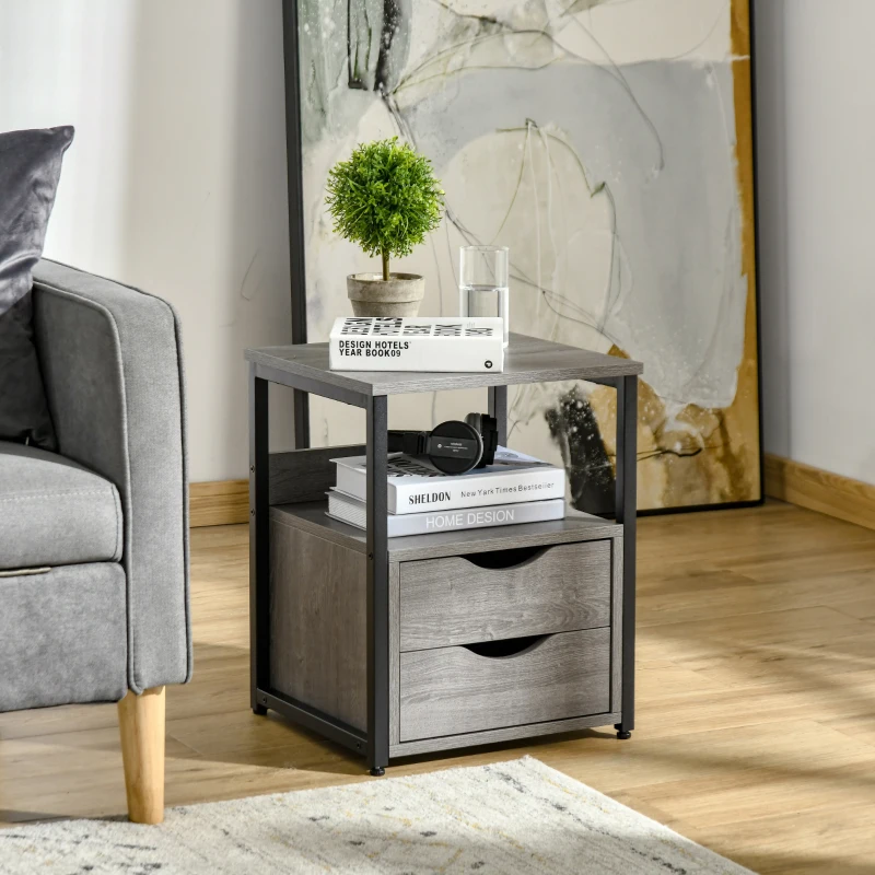 Compact grey end table with drawers, styled with books and a small plant near a lounge chair.