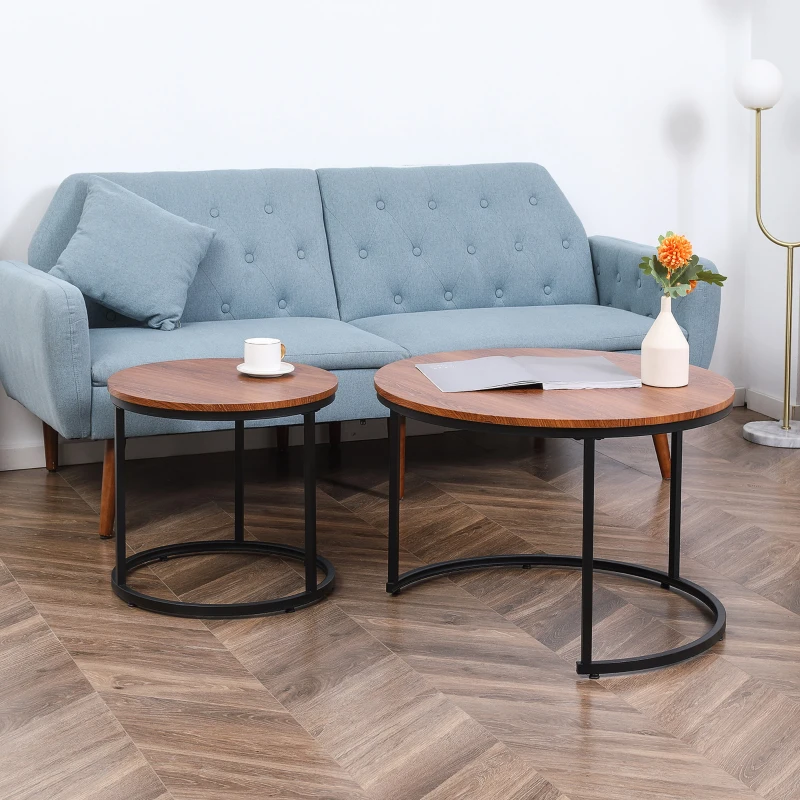 Set of two round wood-top coffee tables with black metal frames beside a light blue sofa.
