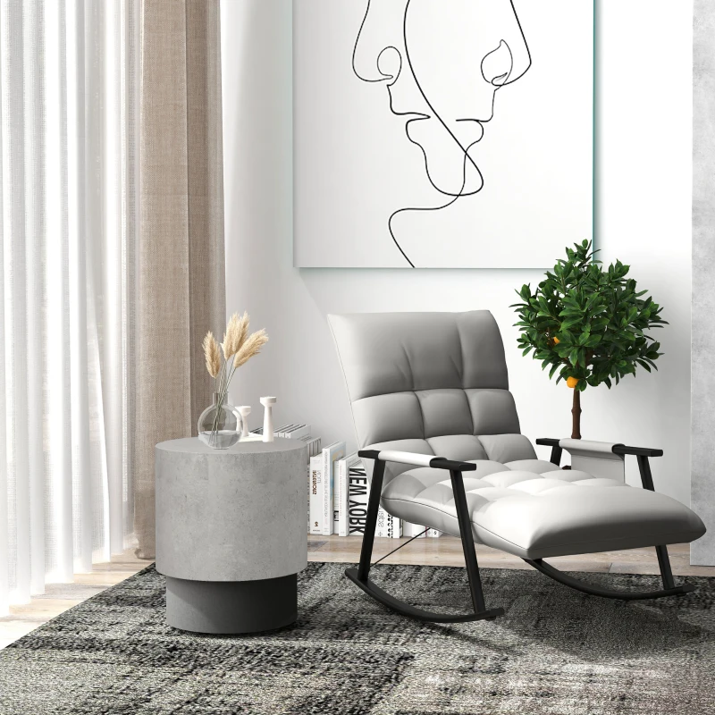 Minimalist round end table beside a modern rocking chair, decorated with books and a clear vase.