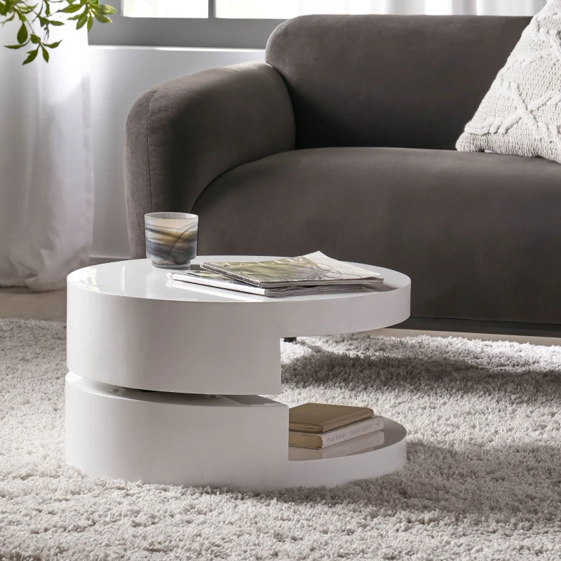 Stylish coffee table with decorative items in a bright room with a grey sofa and sheer curtains.
