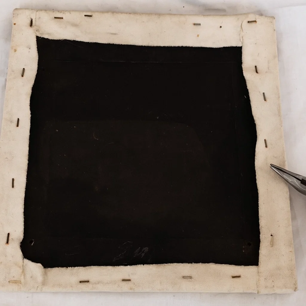 Seat base with old fabric removed and staples exposed on all edges