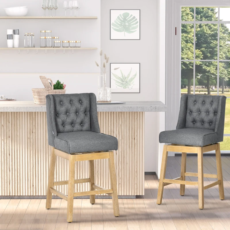 Two gray tufted swivel bar stools with light wood legs at a home bar with large windows.