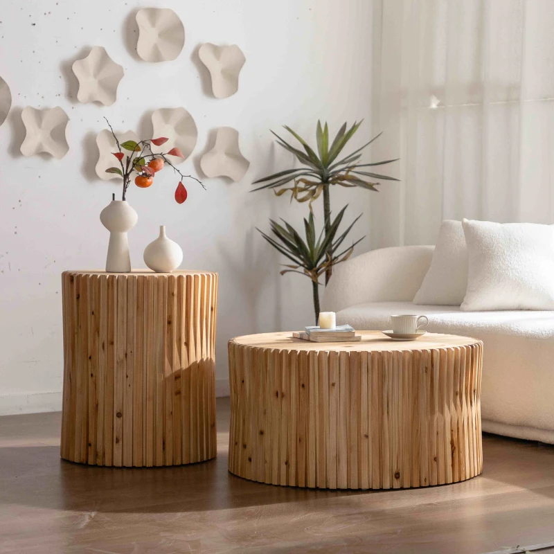 Glossy white round coffee table with shelf, styled simply with a candle and book near a plush sofa.
